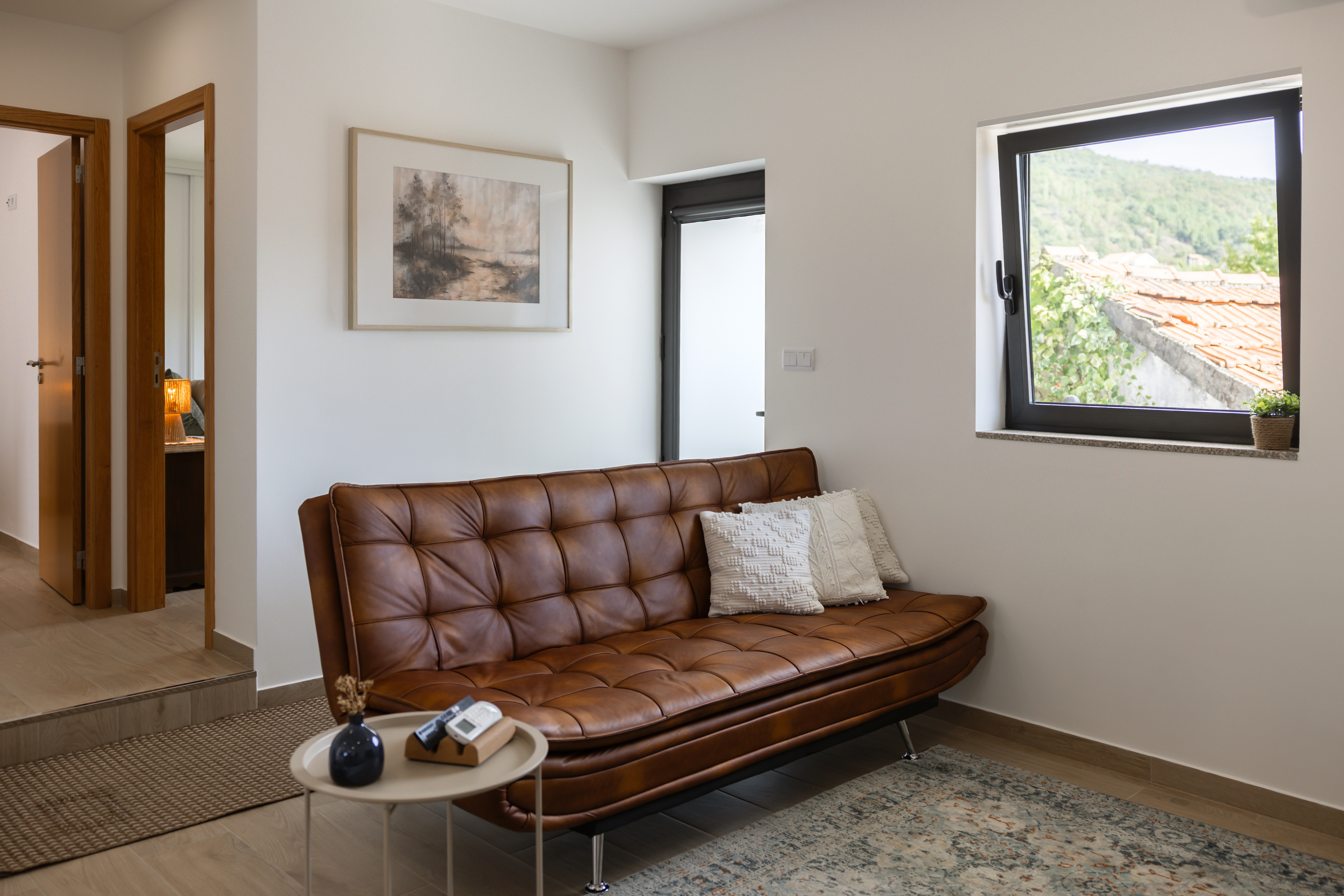 Sala de estar com sofá em pele castanha e quadro emoldurado